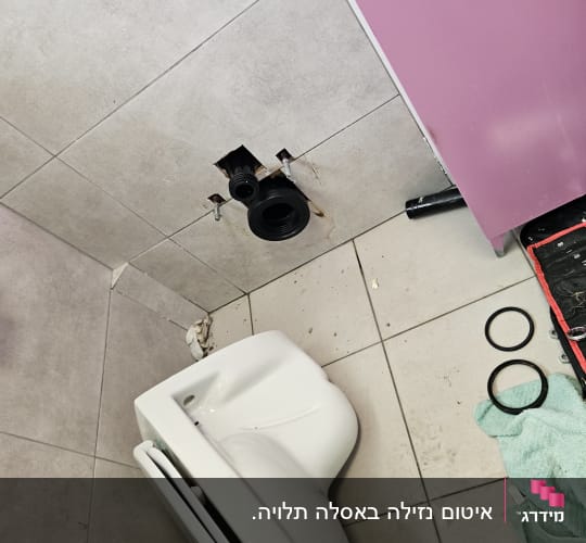 אסלה מנותקת עם חיבורים וכלים על הרצפה